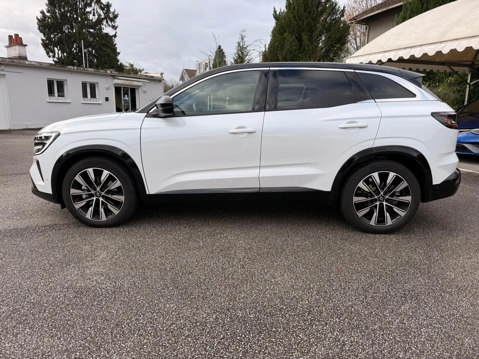 Profil droit d'un Renault Austral E-Tech 200 blanc nacré avec toit noir, roues alliage et détails noirs contrastants.