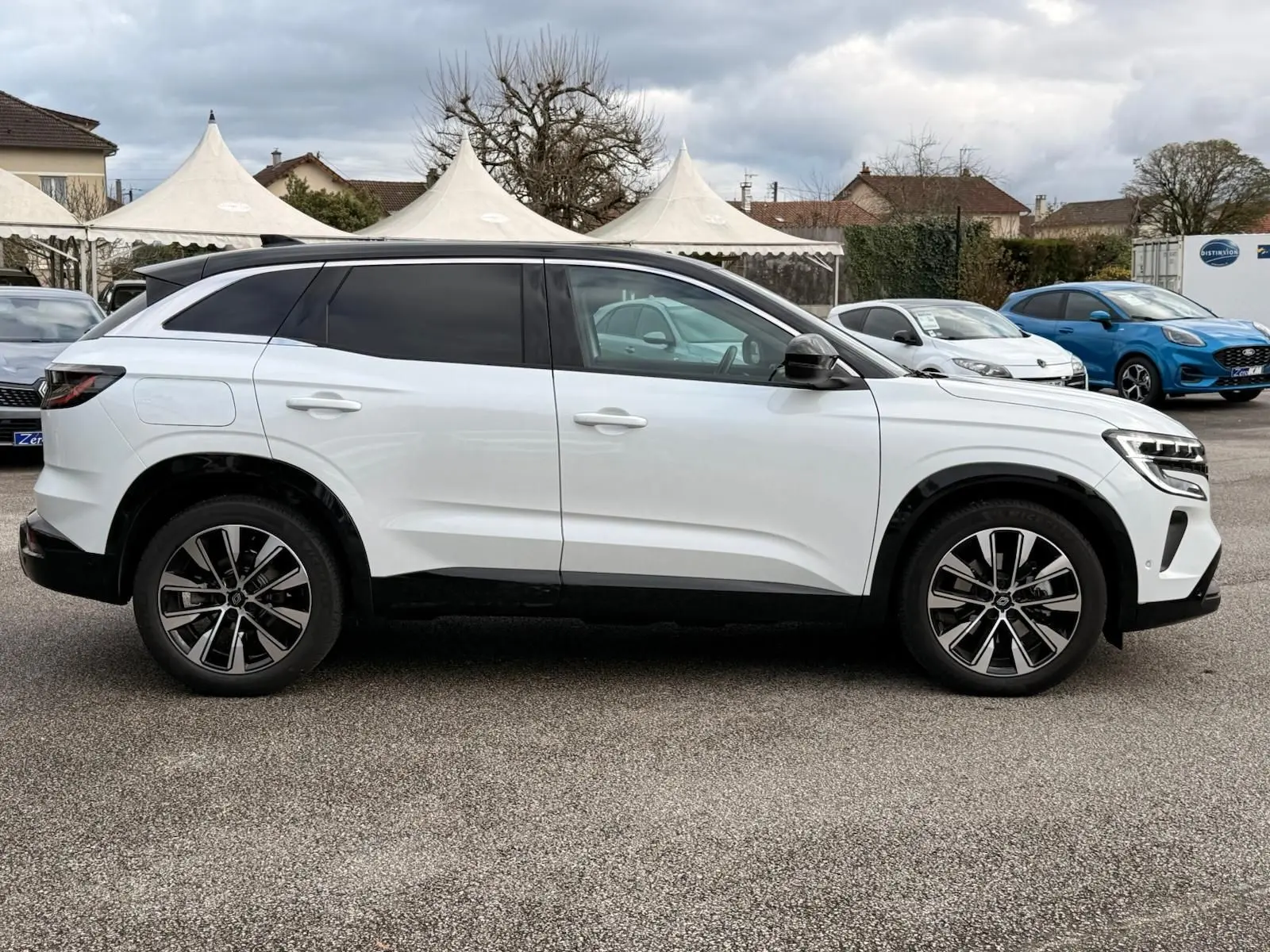 Profil côté gauche du Renault Austral E-Tech 200 blanc nacré avec toit noir, roues alliage et vitres teintées.