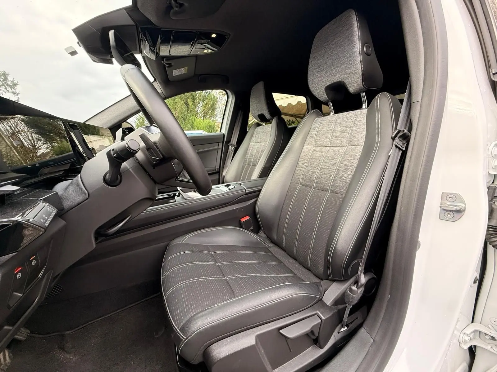 Intérieur côté conducteur du Renault Austral E-Tech 200 blanc nacré, sièges tissu et cuir gris avec surpiqûres blanches.