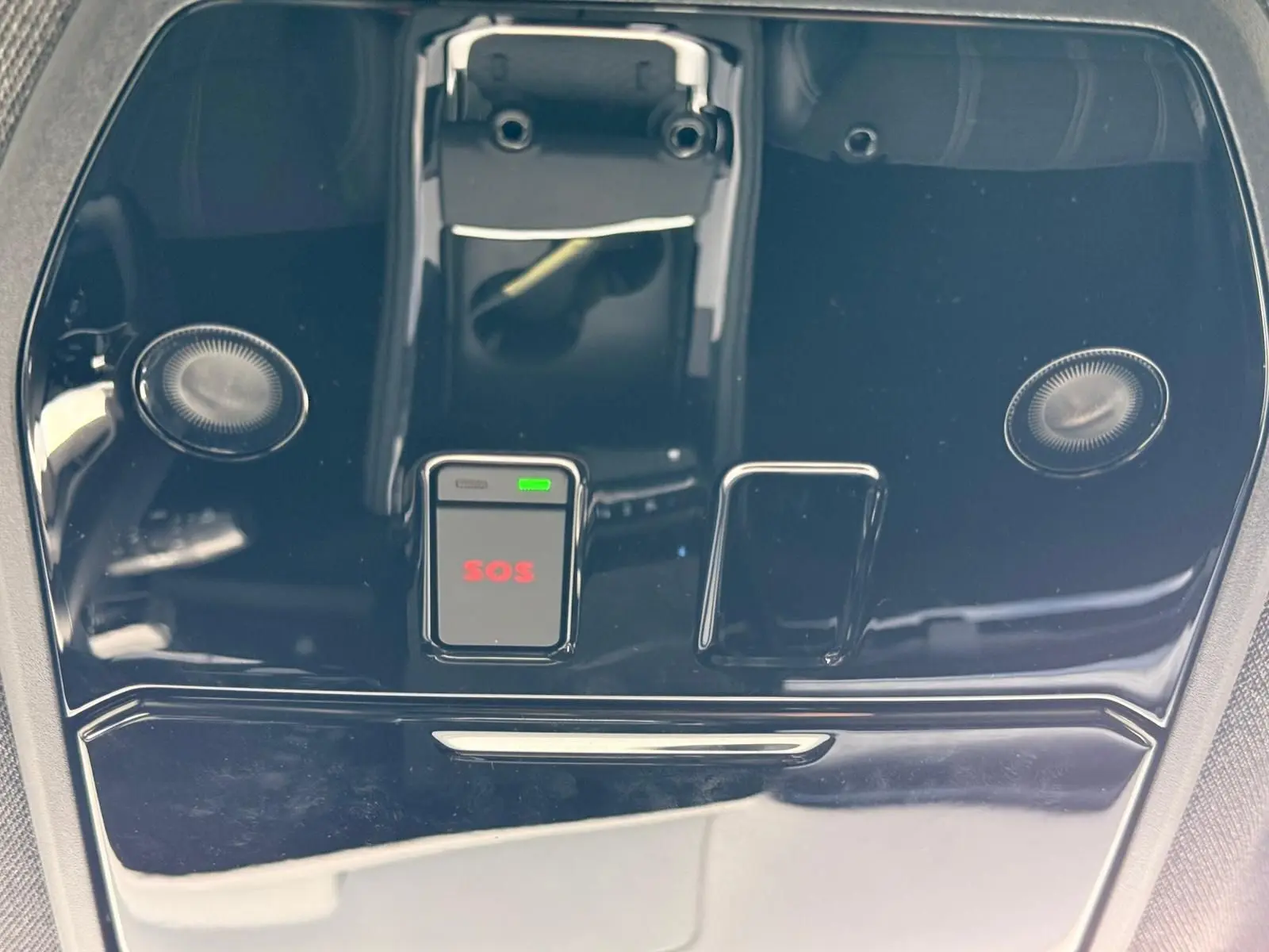 Gros plan sur la console de toit noire brillante du Renault Austral E-Tech 200 blanc nacré avec bouton SOS rouge.