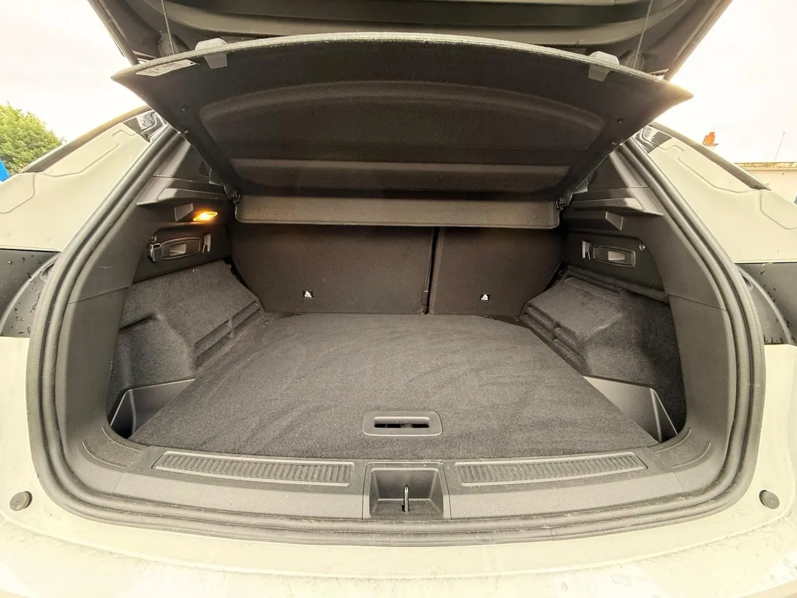 Coffre ouvert du Renault Austral E-Tech 200 blanc nacré avec toit noir, montrant un espace de chargement spacieux et bien fini.