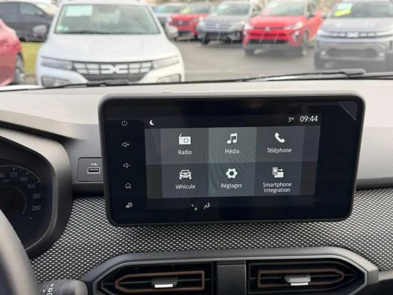 Vue intérieure centrée sur l’écran tactile du tableau de bord de la Dacia Sandero 2025, avec volant partiellement visible.
