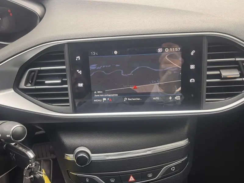 Vue rapprochée de l’écran tactile central du tableau de bord de la Peugeot 308 blanc Banquise, affichant la navigation.