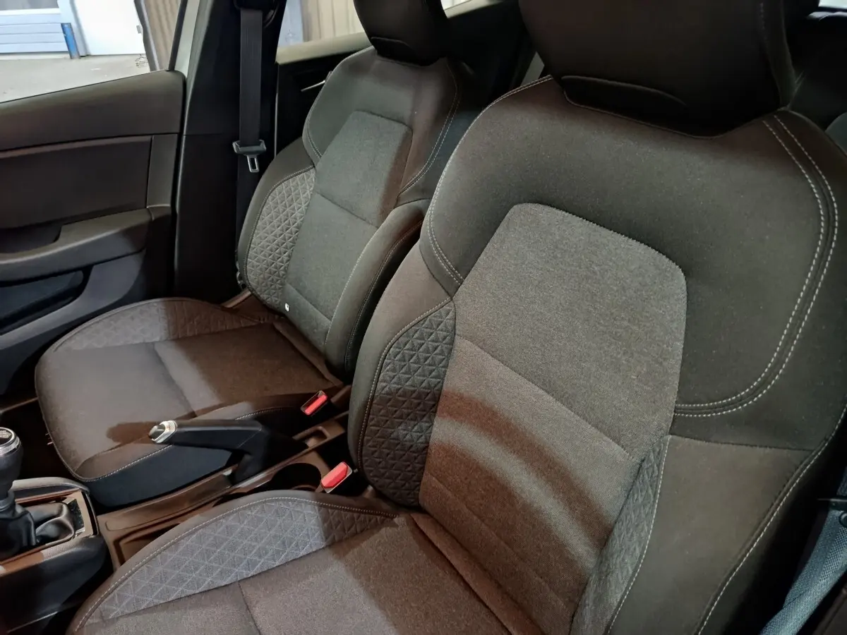 Vue rapprochée des sièges avant gris foncé de la Renault Clio Equilibre TCe 90, avec console centrale et frein à main visible.