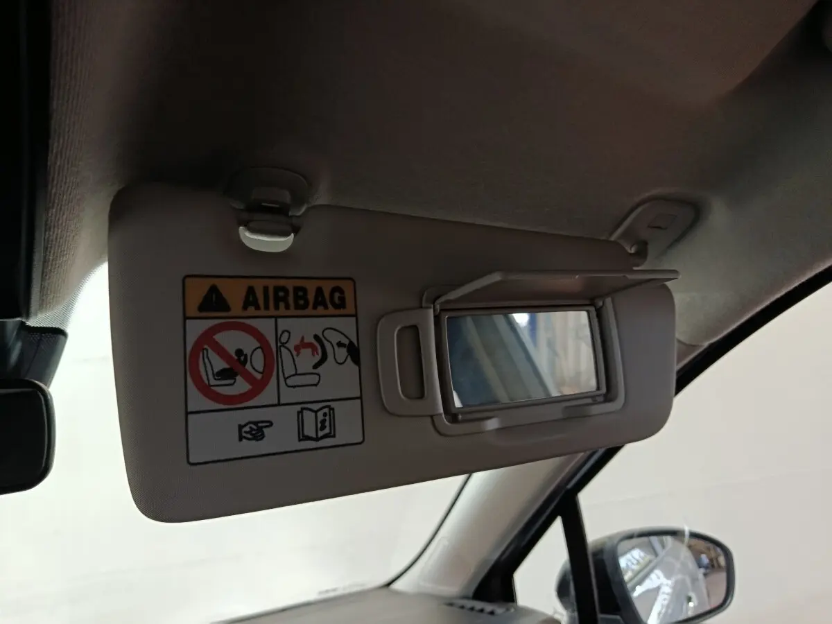 Vue intérieure rapprochée du pare-soleil côté conducteur avec miroir et avertissement airbag dans une Renault Clio gris clair.