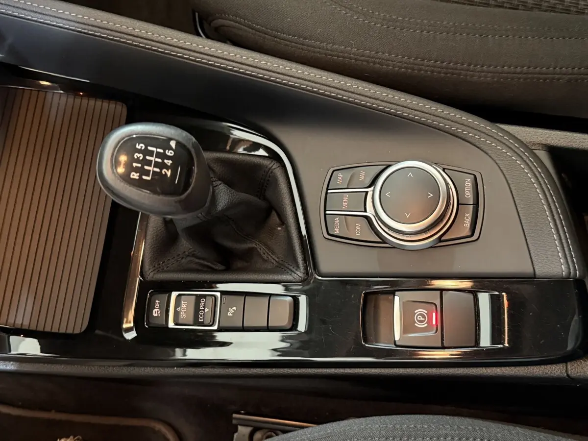 Vue rapprochée de la console centrale noire du BMW X2 sDrive18i 2023 avec levier de vitesse manuel et molette de sélection.