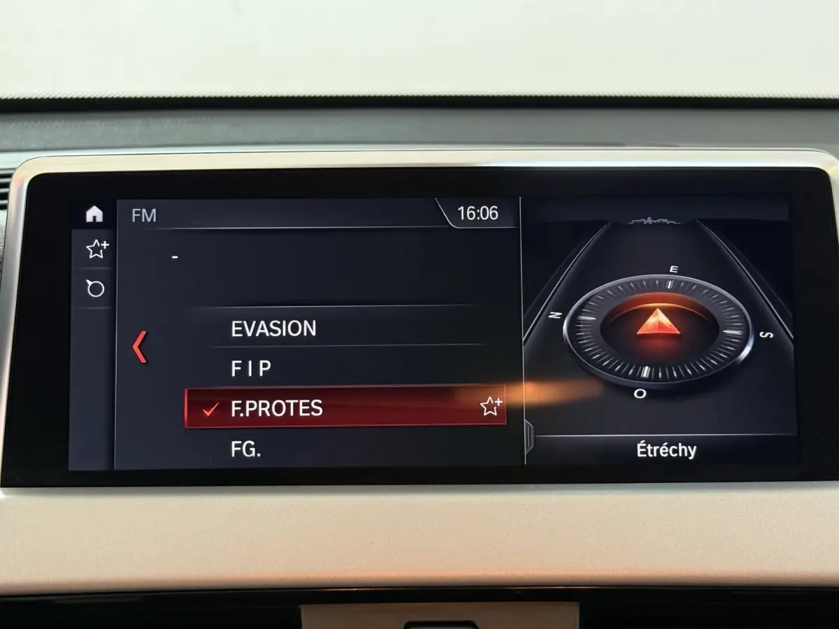 Écran central du tableau de bord de la BMW X2 sDrive18i Lounge 2023 affichant la navigation et la radio FM.