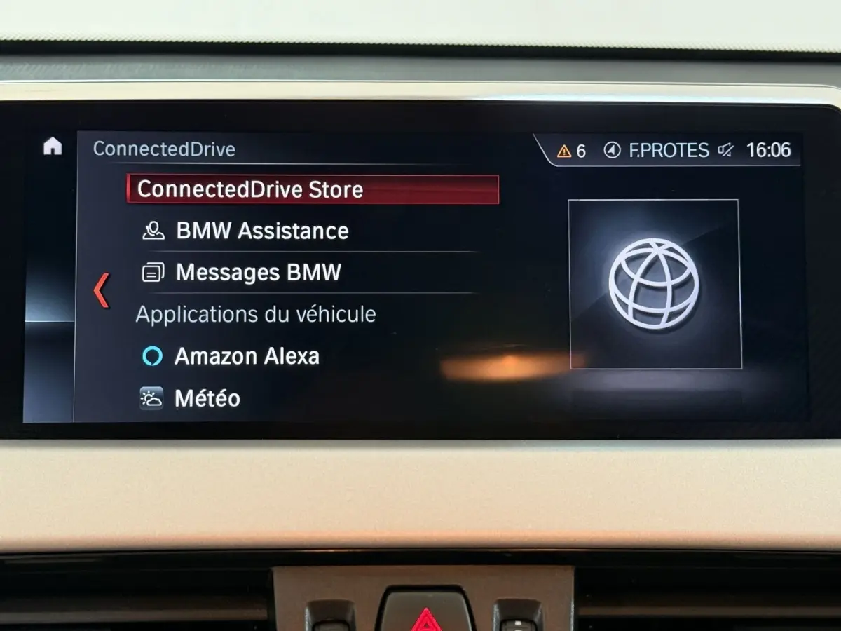 Écran central du tableau de bord du BMW X2 sDrive18i 2023 affichant le menu ConnectedDrive en intérieur beige.