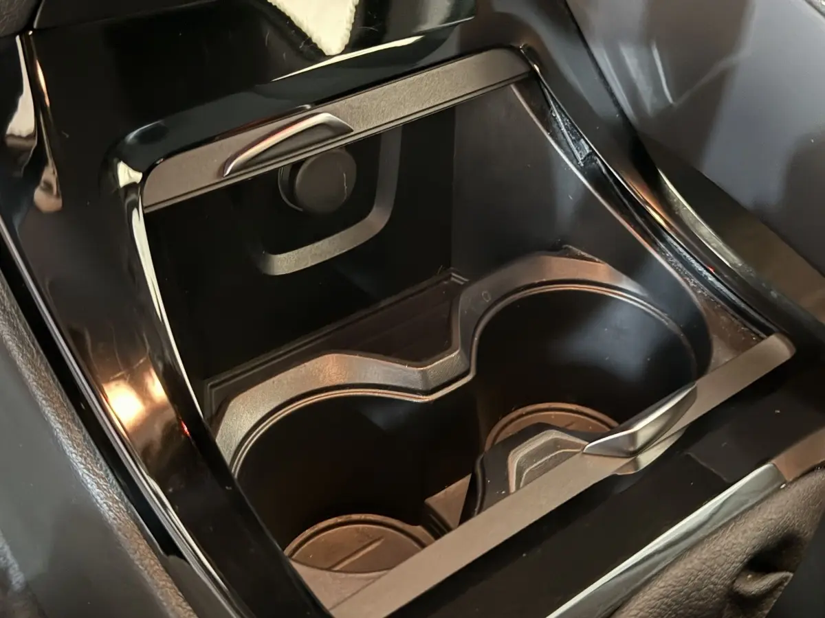 Gros plan sur les porte-gobelets noirs et la console centrale brillante de la BMW X2 sDrive18i Lounge 2023.