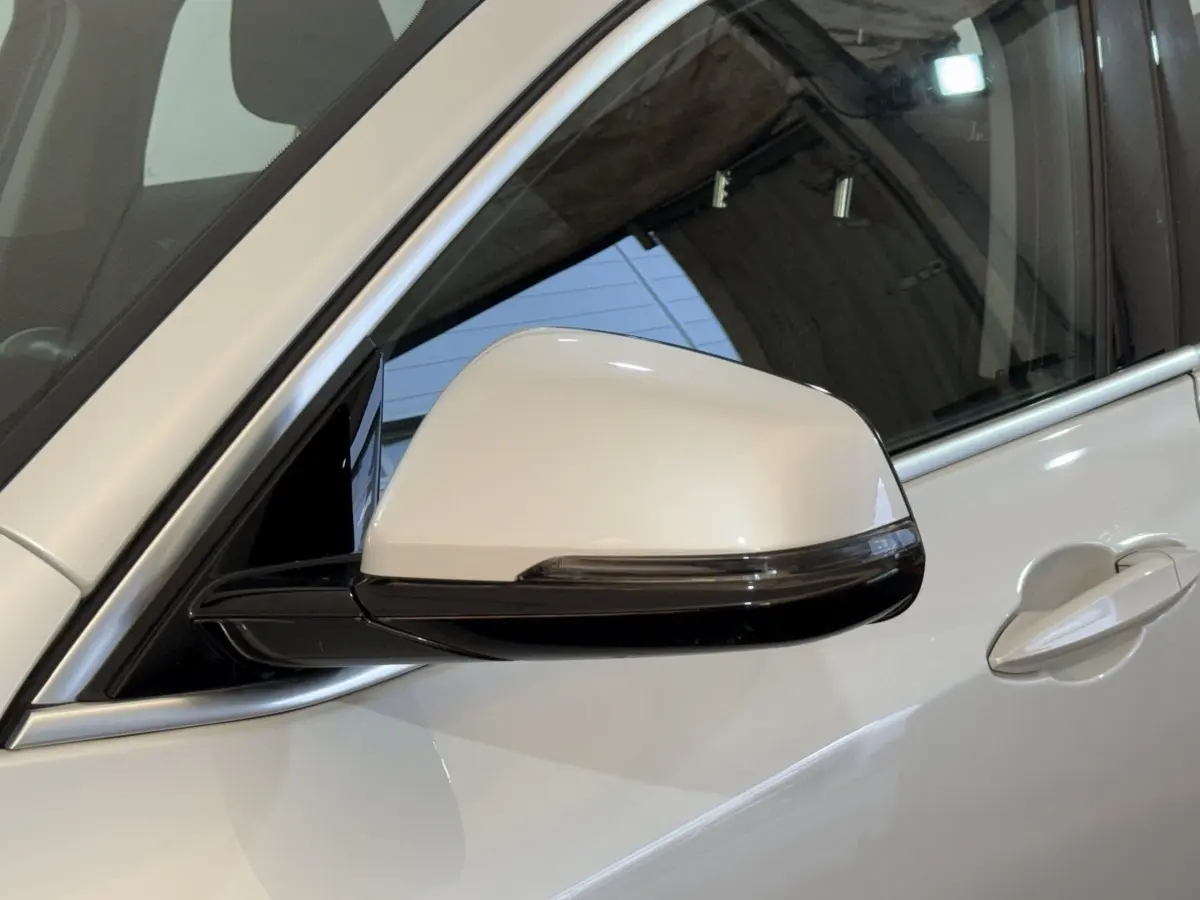 Gros plan sur le rétroviseur côté gauche blanc du BMW X2 sDrive18i Lounge 2023 avec poignée de porte assortie.