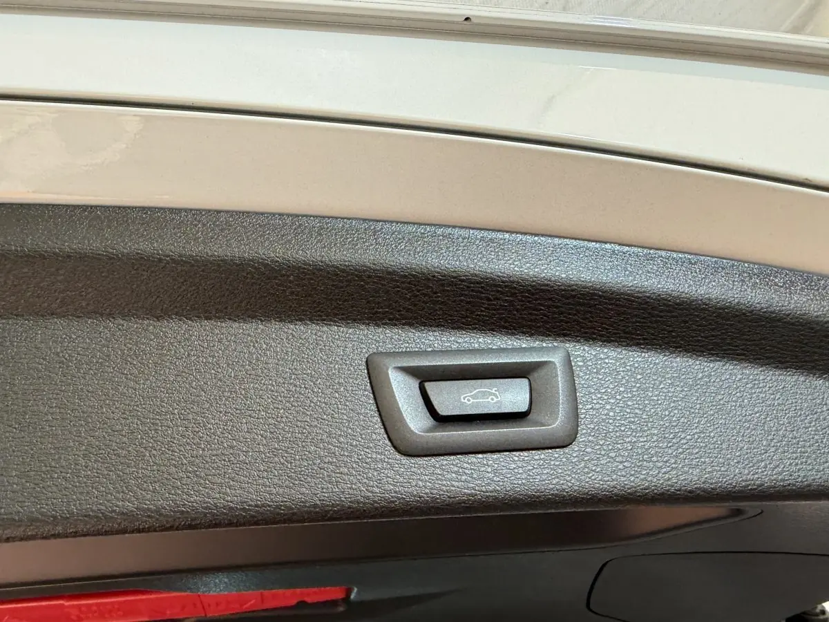 Bouton d'ouverture électrique du coffre sur le hayon intérieur d'un BMW X2 blanc, vue rapprochée.