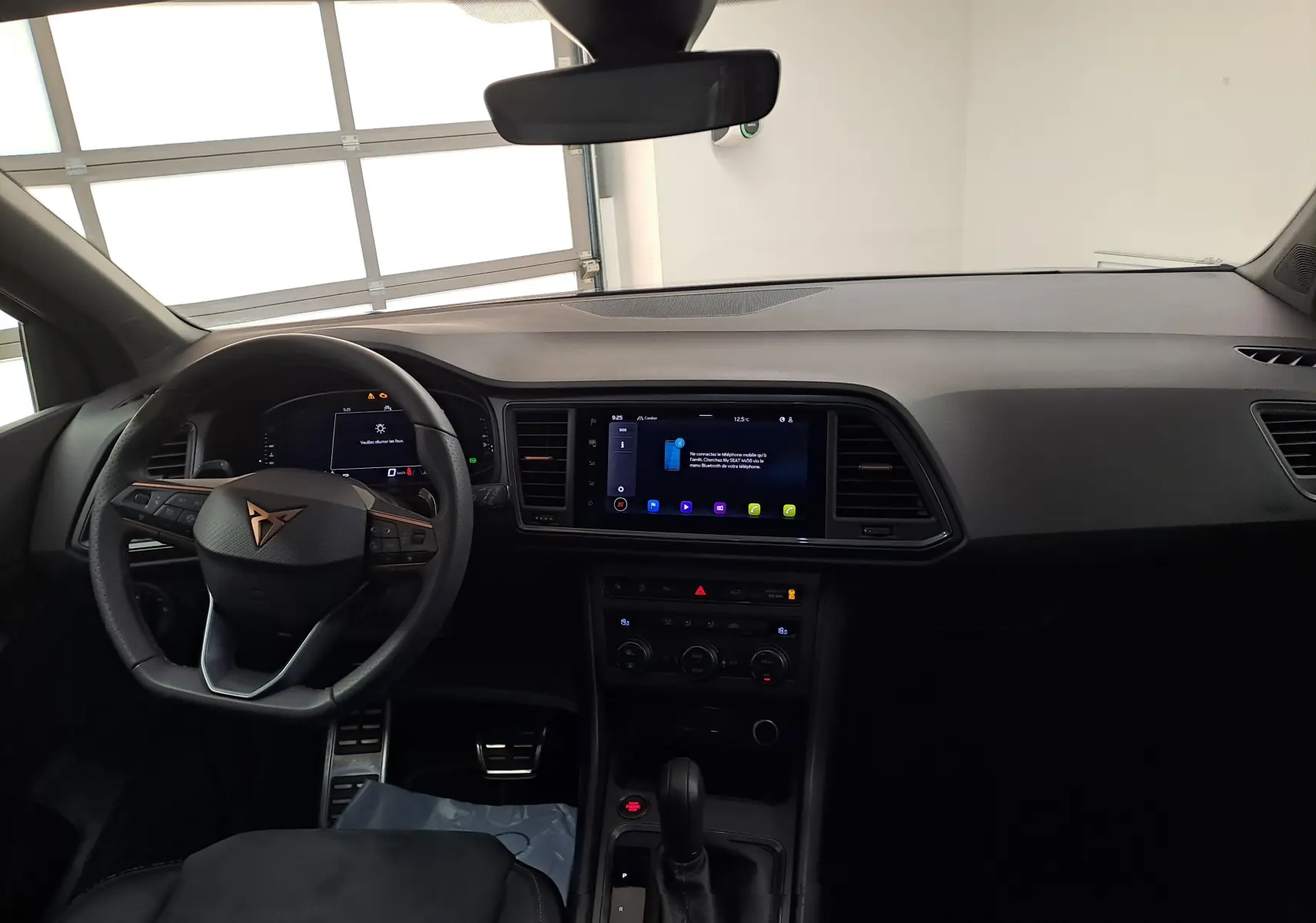 Vue intérieure du tableau de bord et volant du CUPRA Ateca 2024 noir magique, avec écran tactile central et boîte automatique.