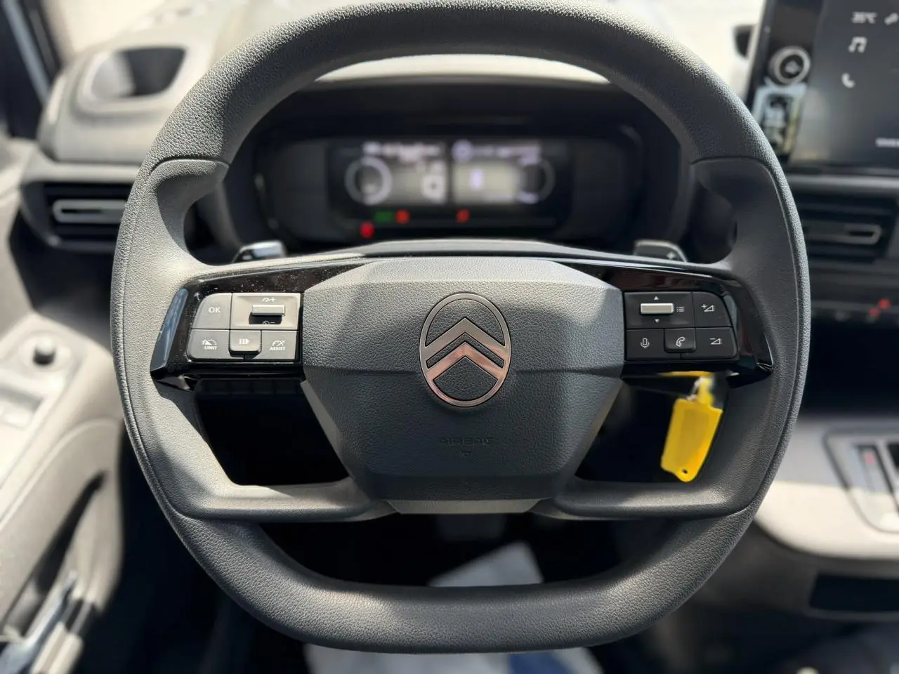 Vue rapprochée du volant multifonction noir du Citroën Berlingo ë-136 2025 avec commandes intégrées et logo central.