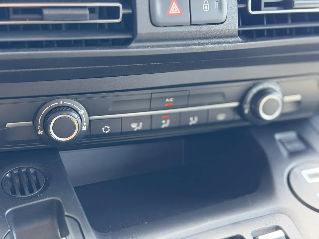 Gros plan sur la console centrale du Citroën Berlingo ë-136 gris Artense, montrant les commandes de climatisation et ventilation.