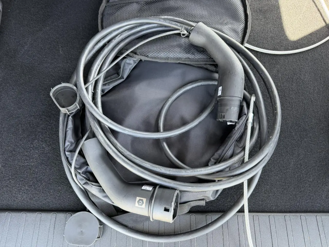 Câble de recharge électrique noir enroulé dans le coffre d’un Citroën Berlingo gris Artense.