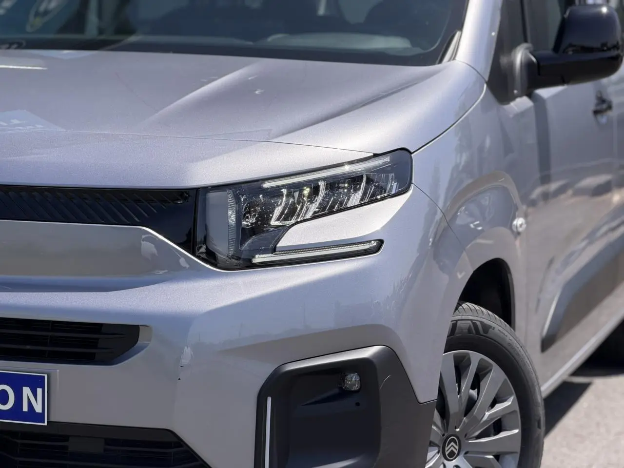 Vue 3/4 avant droit du Citroën Berlingo ë-136 gris Artense avec phares LED et jantes tôles 16 pouces.