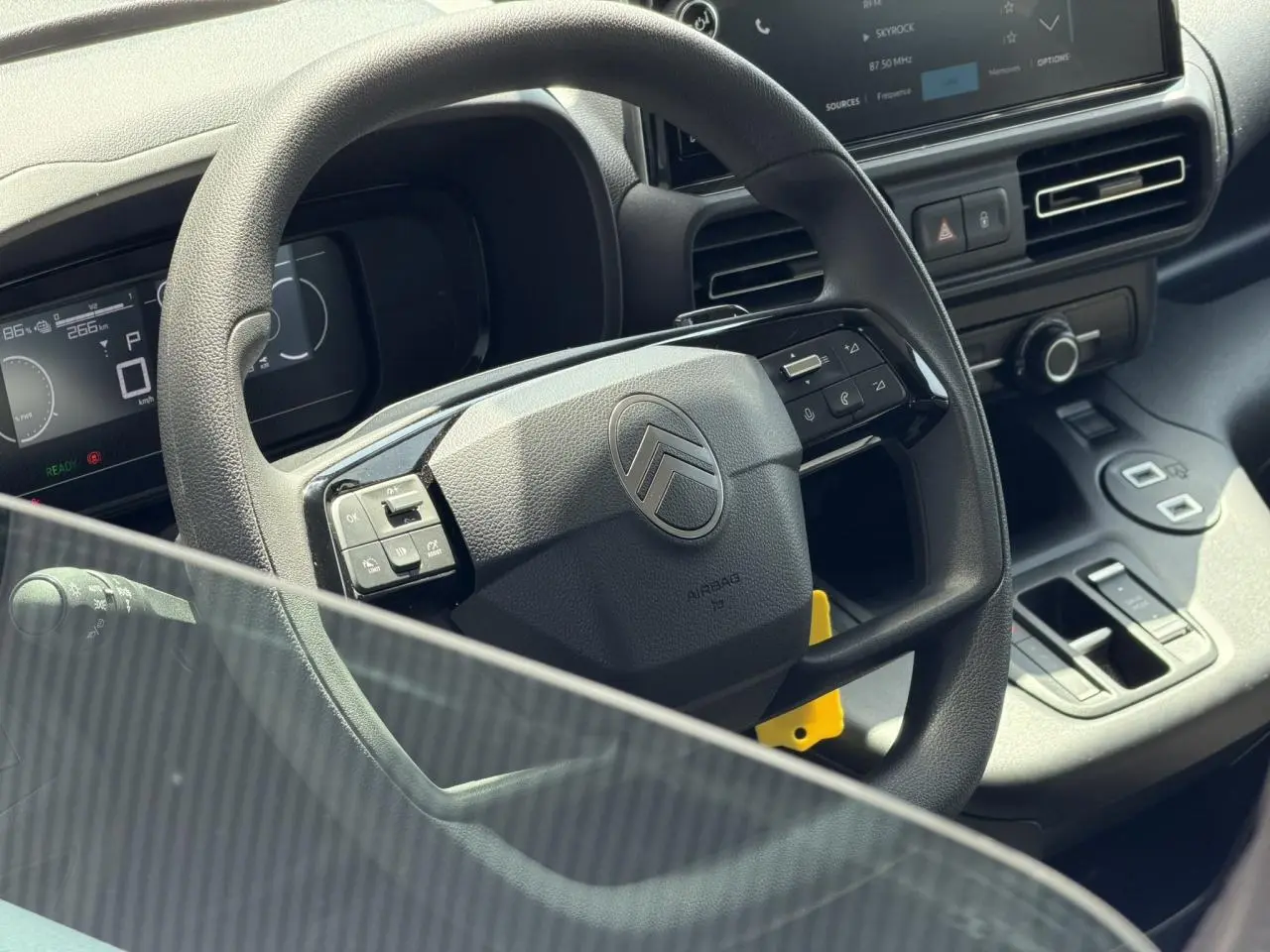 Vue rapprochée du volant et tableau de bord du Citroën Berlingo gris Artense avec écran tactile et commandes intégrées.
