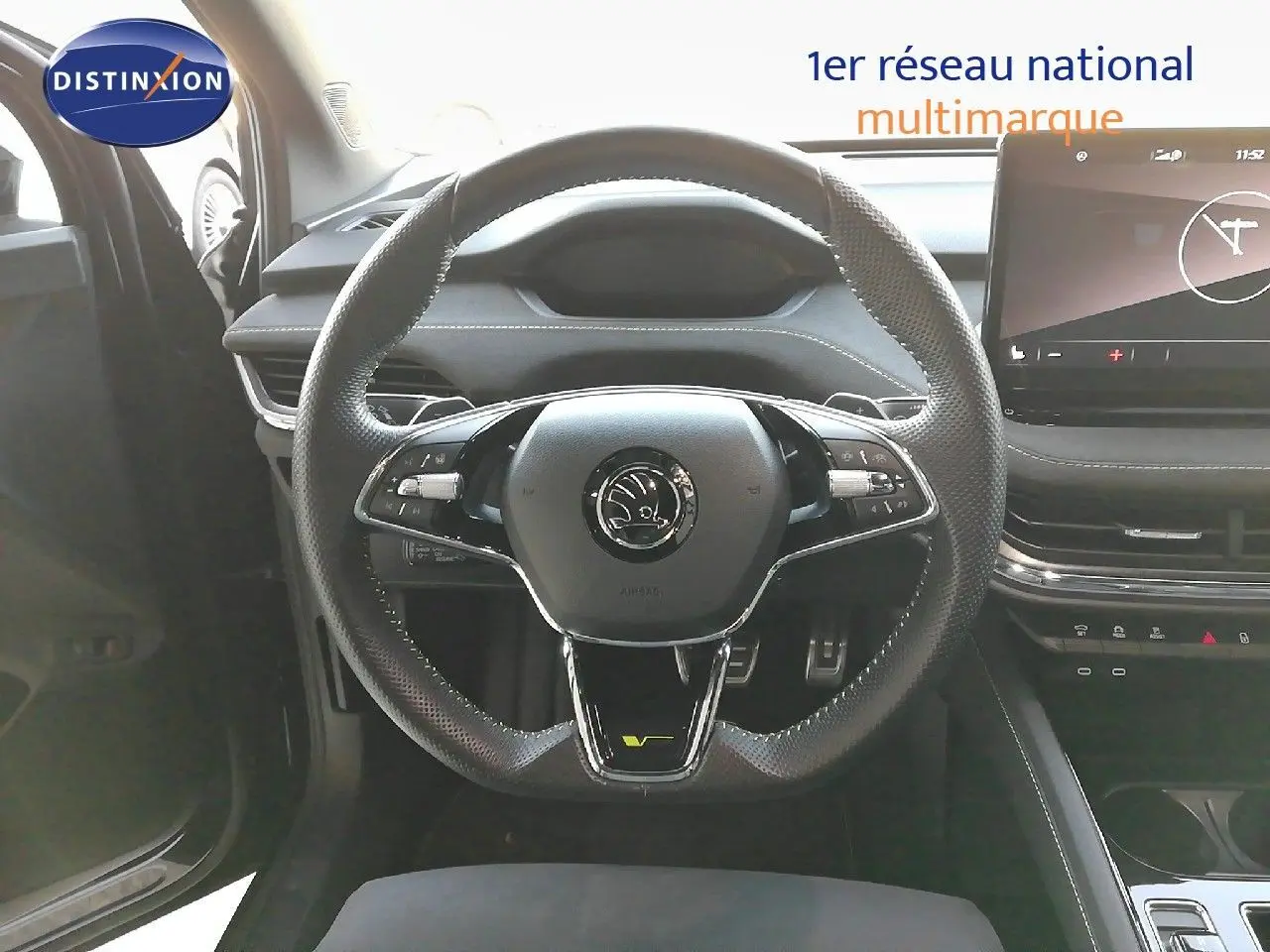 Vue intérieure centrée sur le volant perforé noir du Skoda Enyaq Coupe RS électrique avec tableau de bord moderne.