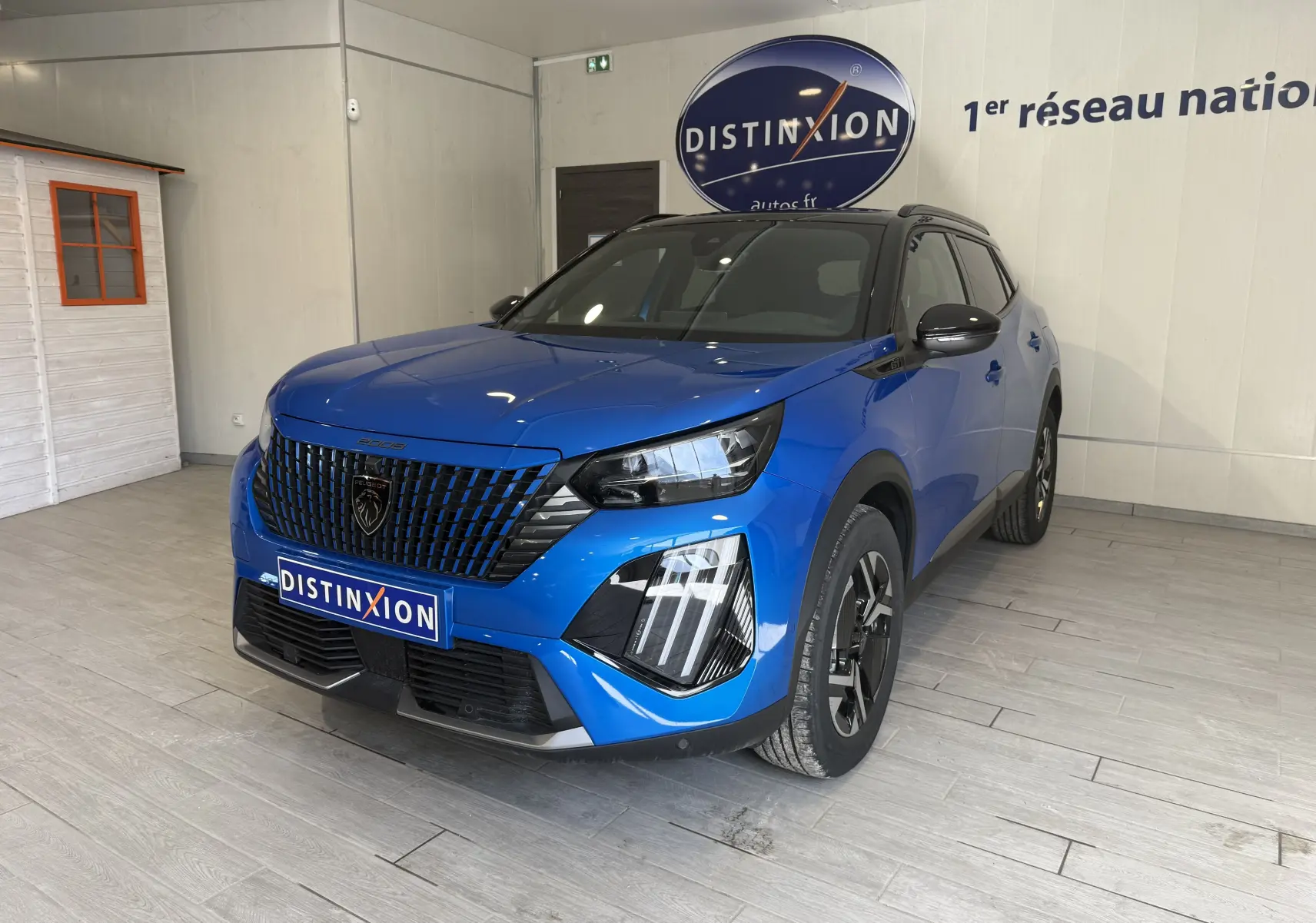 Peugeot 2008 GT bleu Vertigo métal avec toit noir, vue 3/4 avant droit en intérieur showroom.