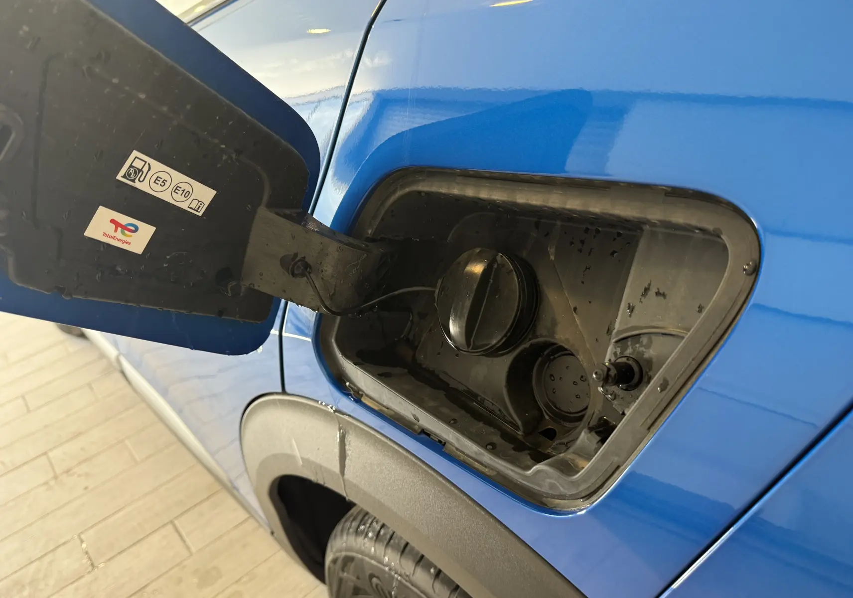 Gros plan sur la trappe à carburant côté gauche d'un Peugeot 2008 bleu Vertigo métal avec toit noir, année 2025.