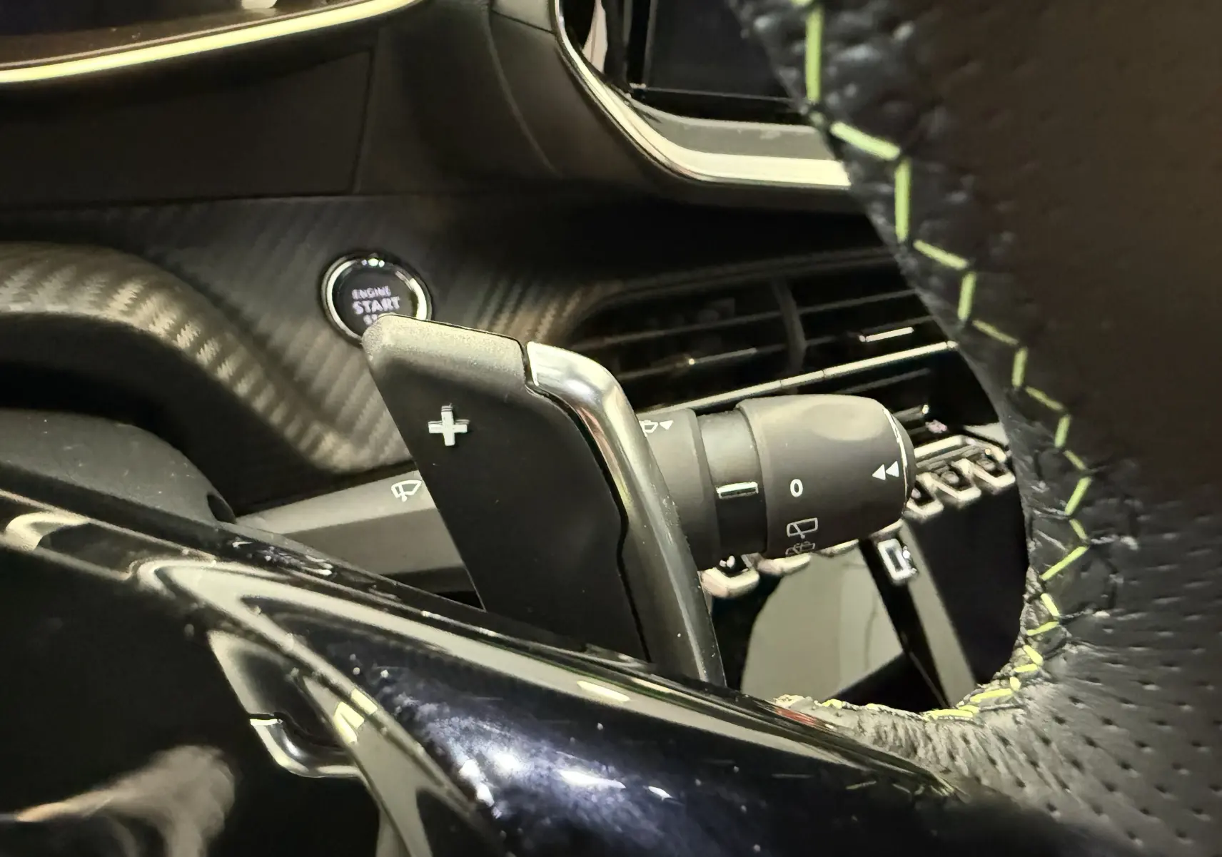 Gros plan sur la palette de changement de vitesse droite et le bouton start du tableau de bord d'une Peugeot 2008 GT 2025.