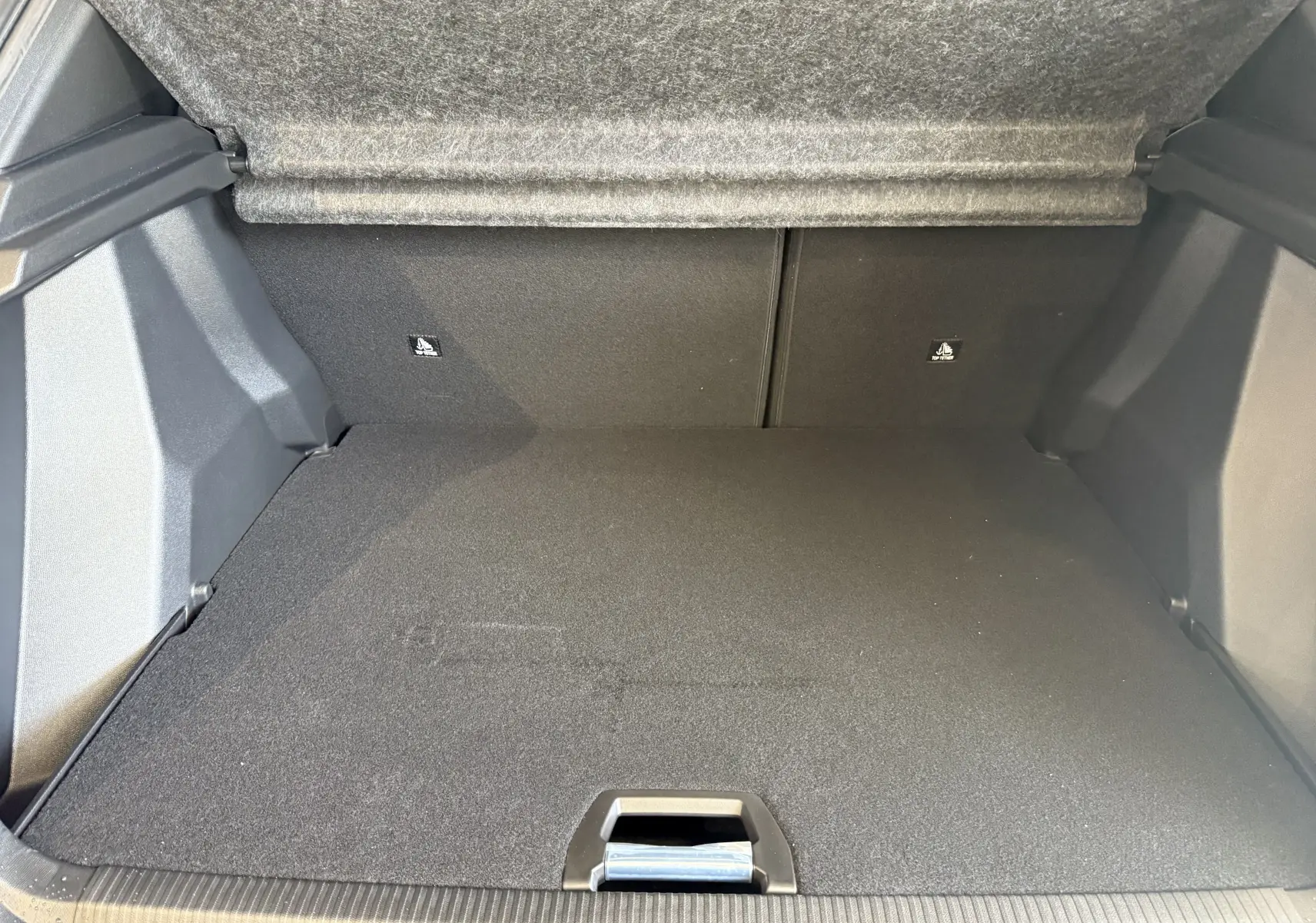 Coffre ouvert du Peugeot 2008 GT 2025, vue intérieure arrière, avec revêtement noir et tapis de sol plat.