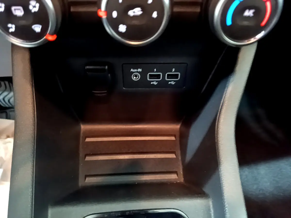 Vue rapprochée de la console centrale noire de la Renault Clio Business TCe 90, avec prises USB et commandes de climatisation.