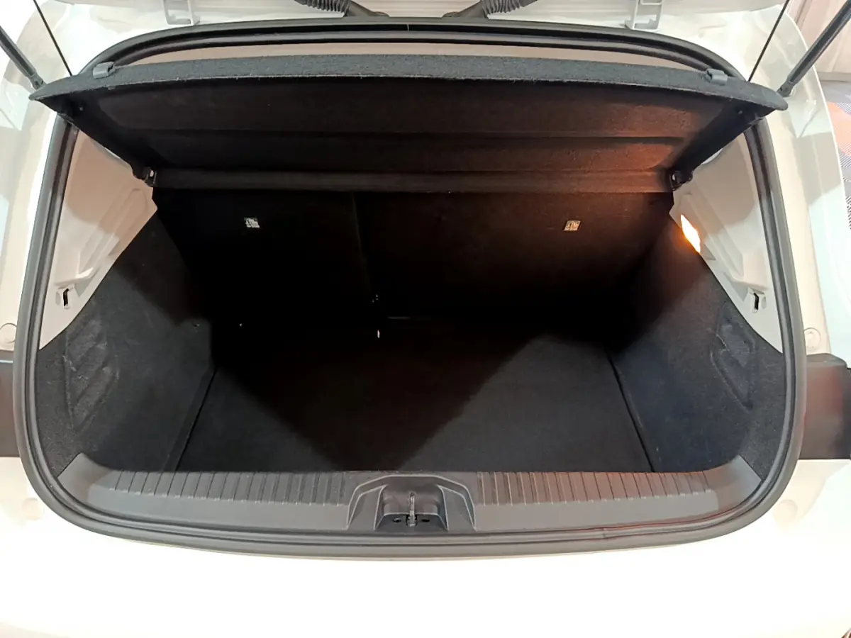 Coffre ouvert vu de l'arrière d'une Renault Clio Business TCe 90 blanche, intérieur noir et éclairage latéral.