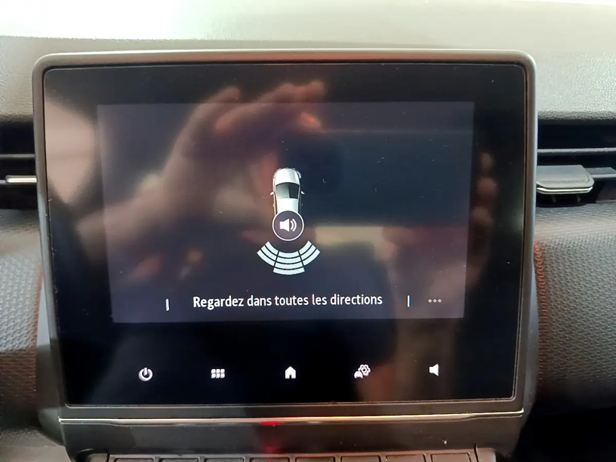 Écran tactile central de la Renault Clio Business blanc montrant l'alerte de capteurs de stationnement arrière.