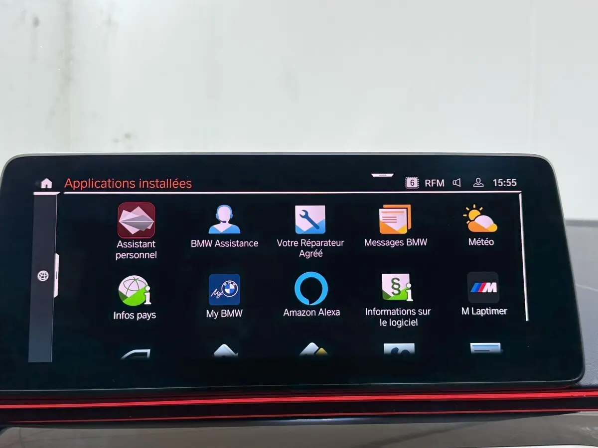 Écran tactile central affichant les applications installées dans une BMW Série 5 Touring noire, vue intérieure.