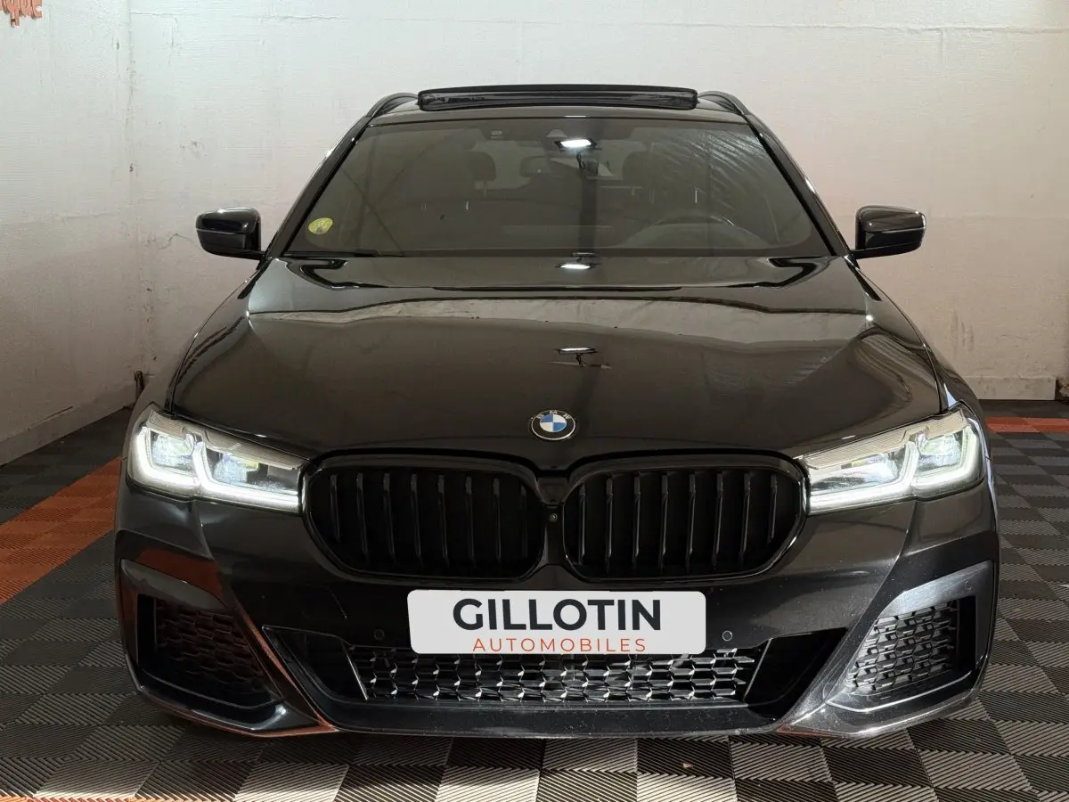 Vue frontale d'une BMW Série 5 Touring 520d noire avec phares LED allumés et calandre noire M Sport.