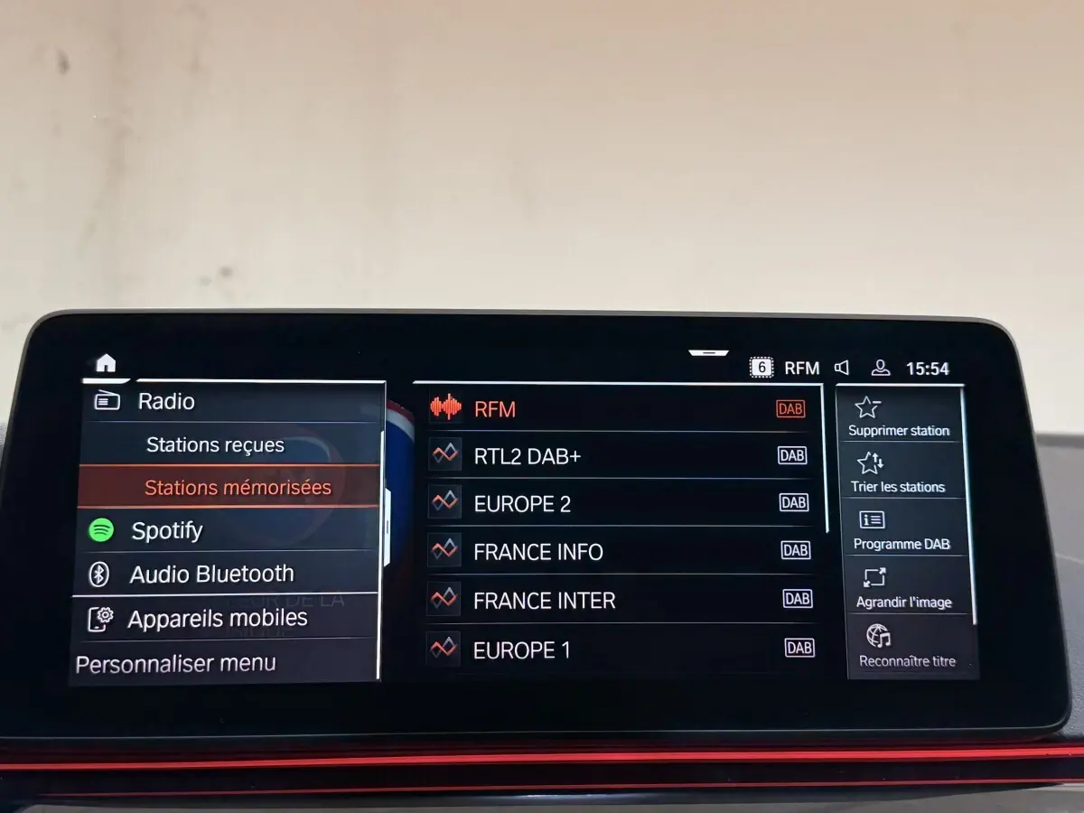 Écran tactile central de BMW Série 5 Touring 520d M Sport 2023 affichant les stations radio en mode DAB.