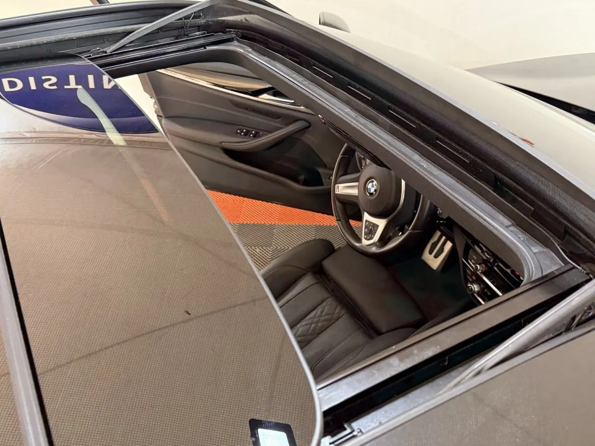 Vue plongeante sur l'intérieur noir de la BMW Série 5 Touring 520d M Sport 2023, avec toit ouvrant ouvert.