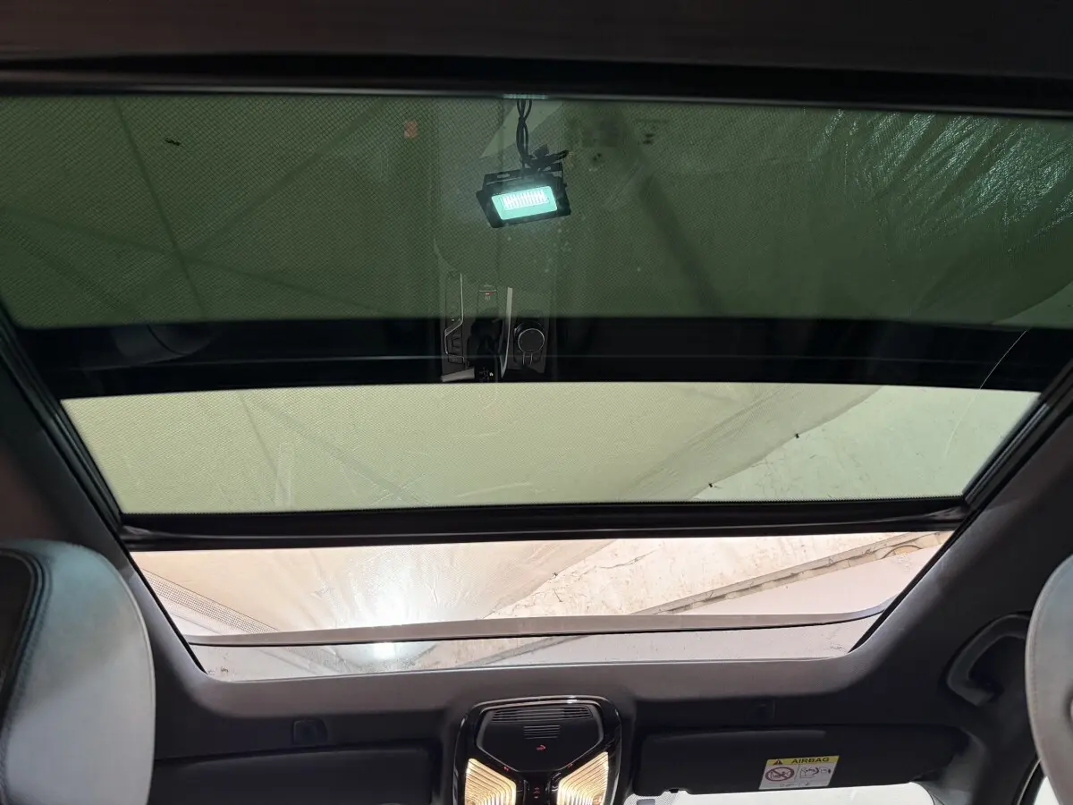 Vue intérieure du toit ouvrant panoramique avec pare-soleil partiellement fermé sur BMW Série 5 Touring noir.