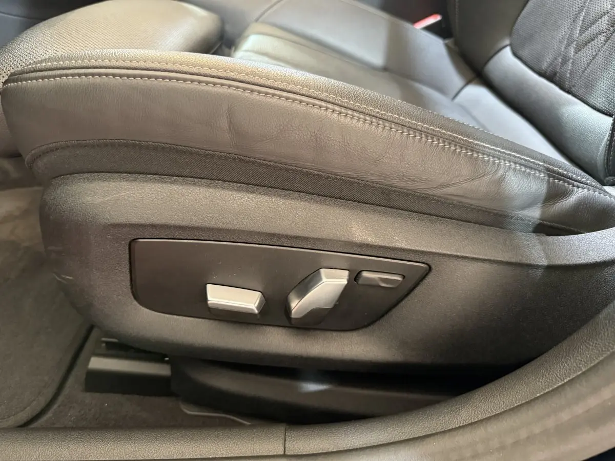 Gros plan sur les commandes de réglage électrique du siège avant en cuir noir d'une BMW Série 5 Touring 520d M Sport.