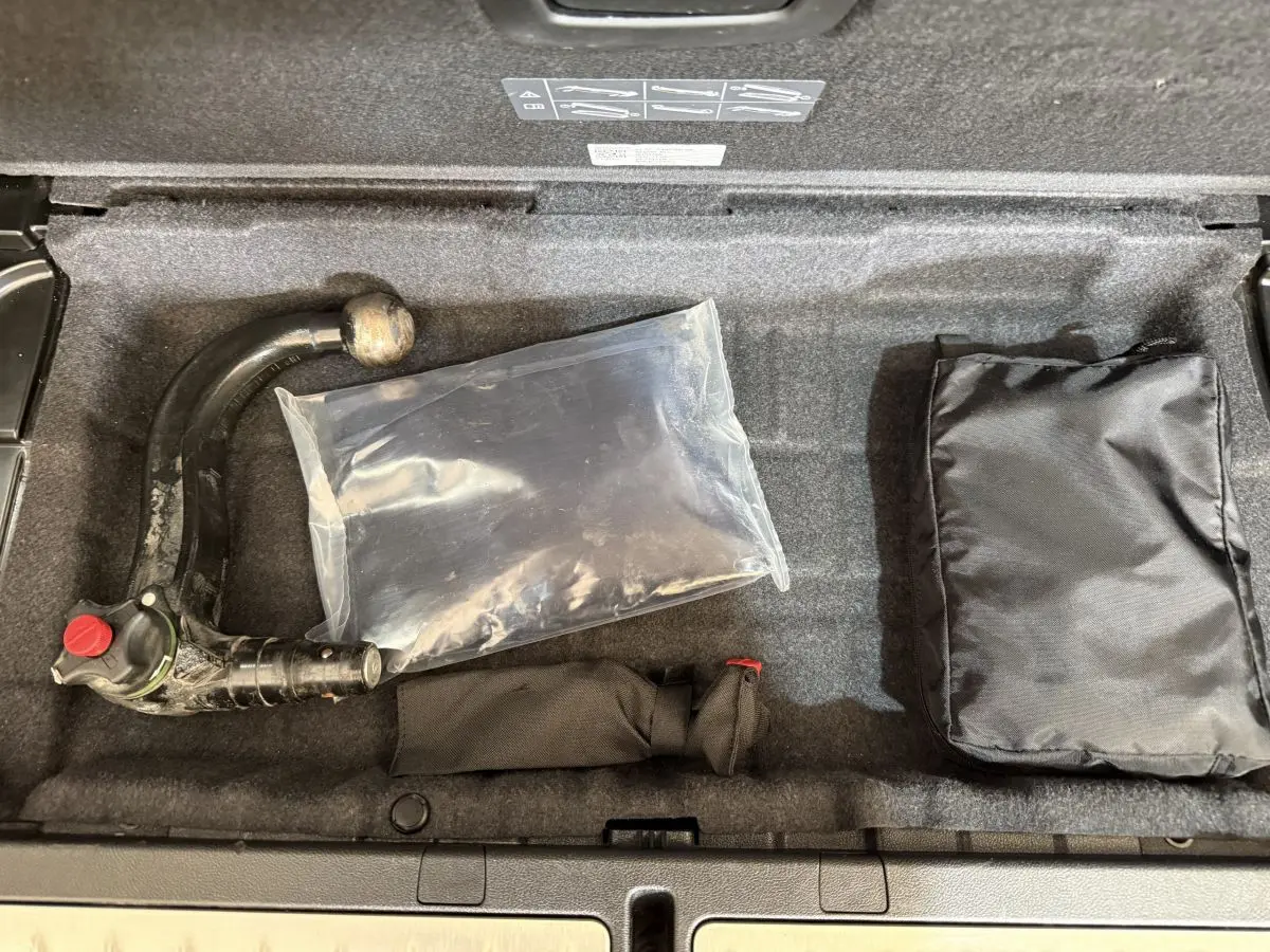 Coffre ouvert d’une BMW Série 5 Touring 520d noir, montrant le rangement sous plancher avec attelage amovible et accessoires.