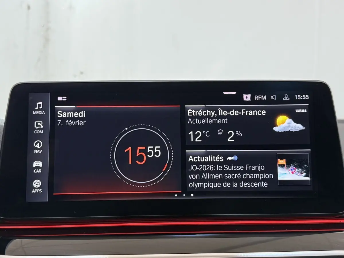 Écran tactile central de la BMW Série 5 Touring 520d M Sport 2023 affichant l'heure, météo et actualités.