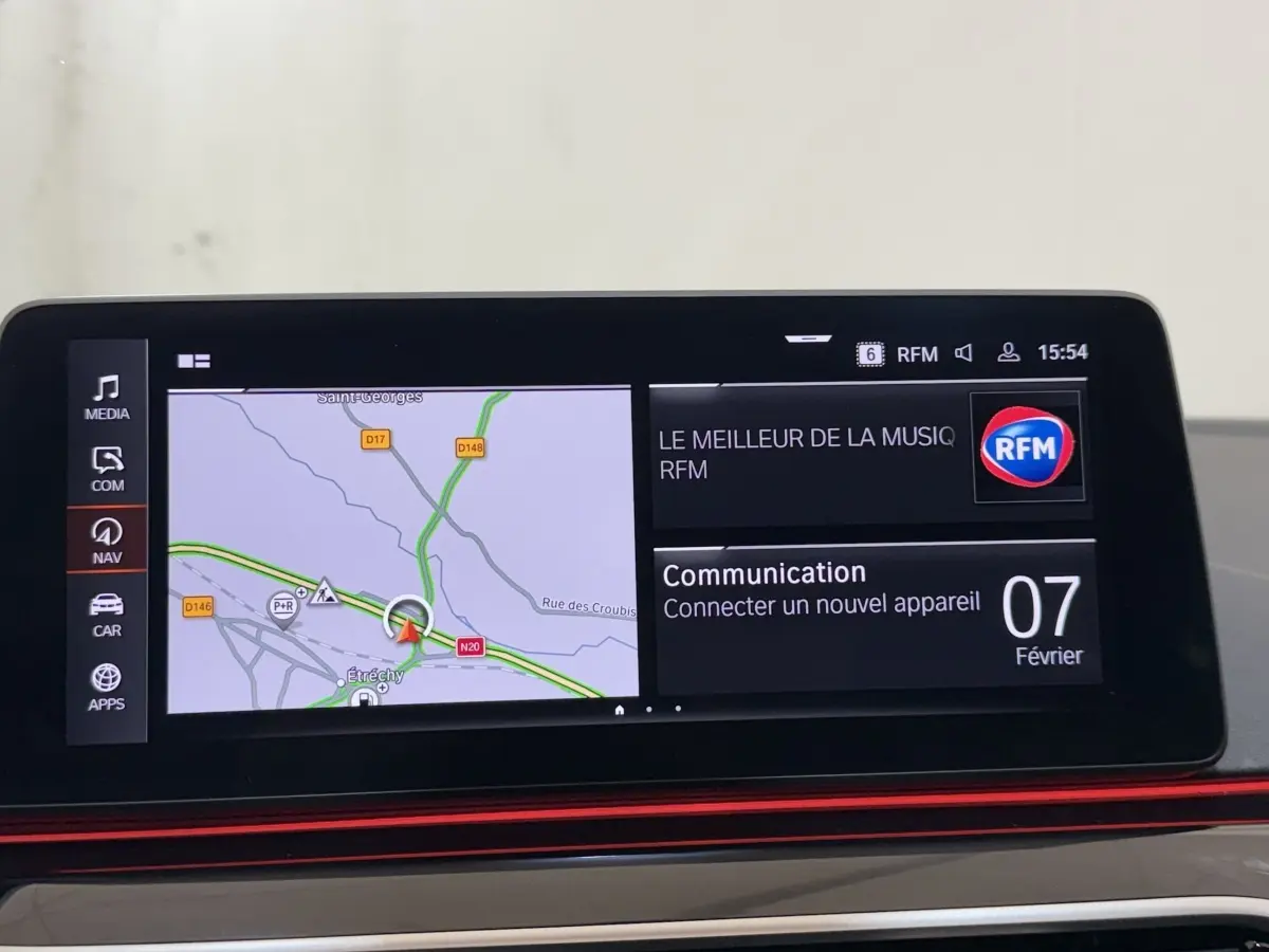 Écran tactile central affichant navigation et communication dans BMW Série 5 Touring noir, vue intérieure frontale.