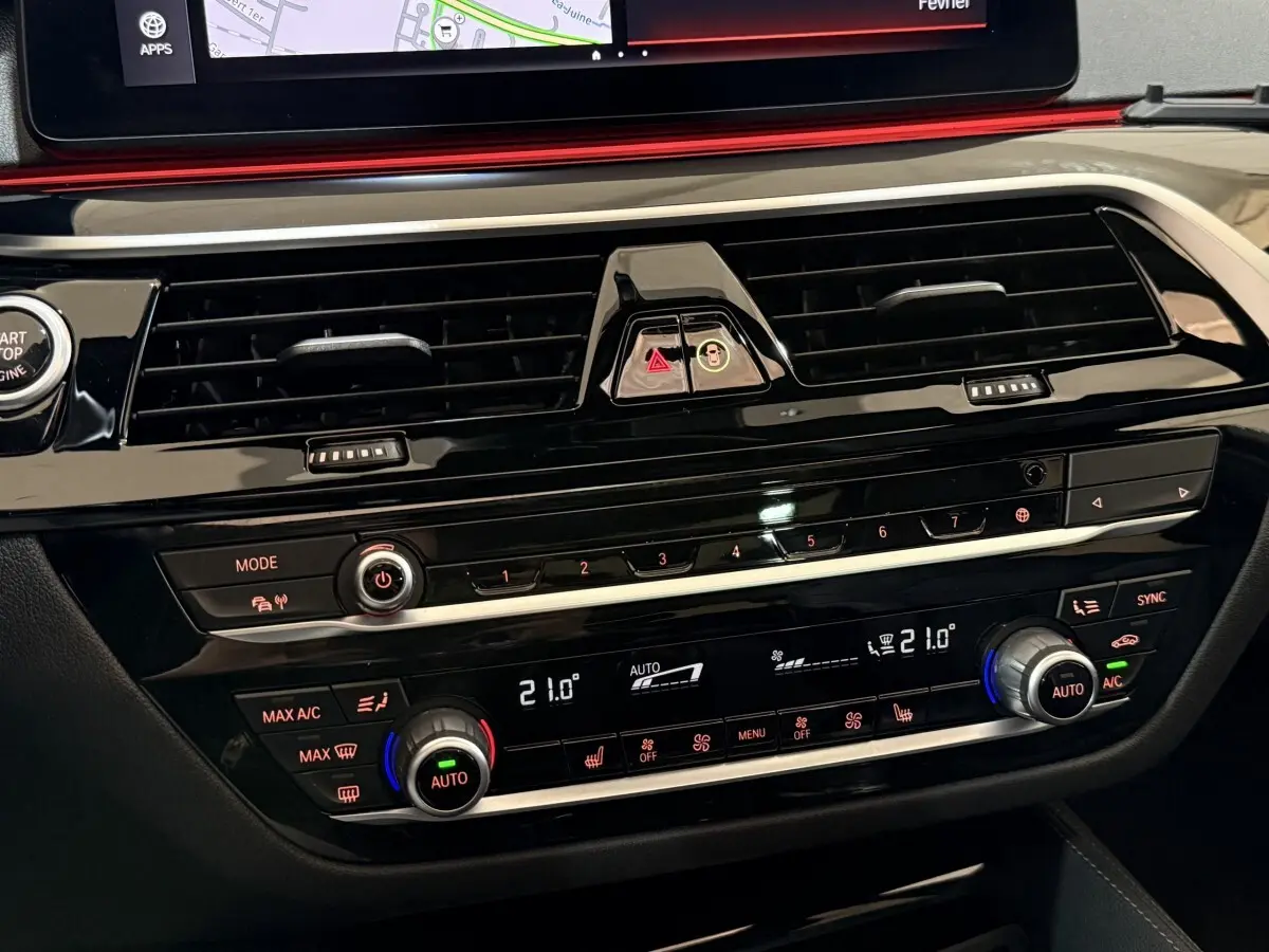 Gros plan sur la console centrale noire brillante de la BMW Série 5 Touring 520d, avec commandes climatisation digitale et écran tactile.