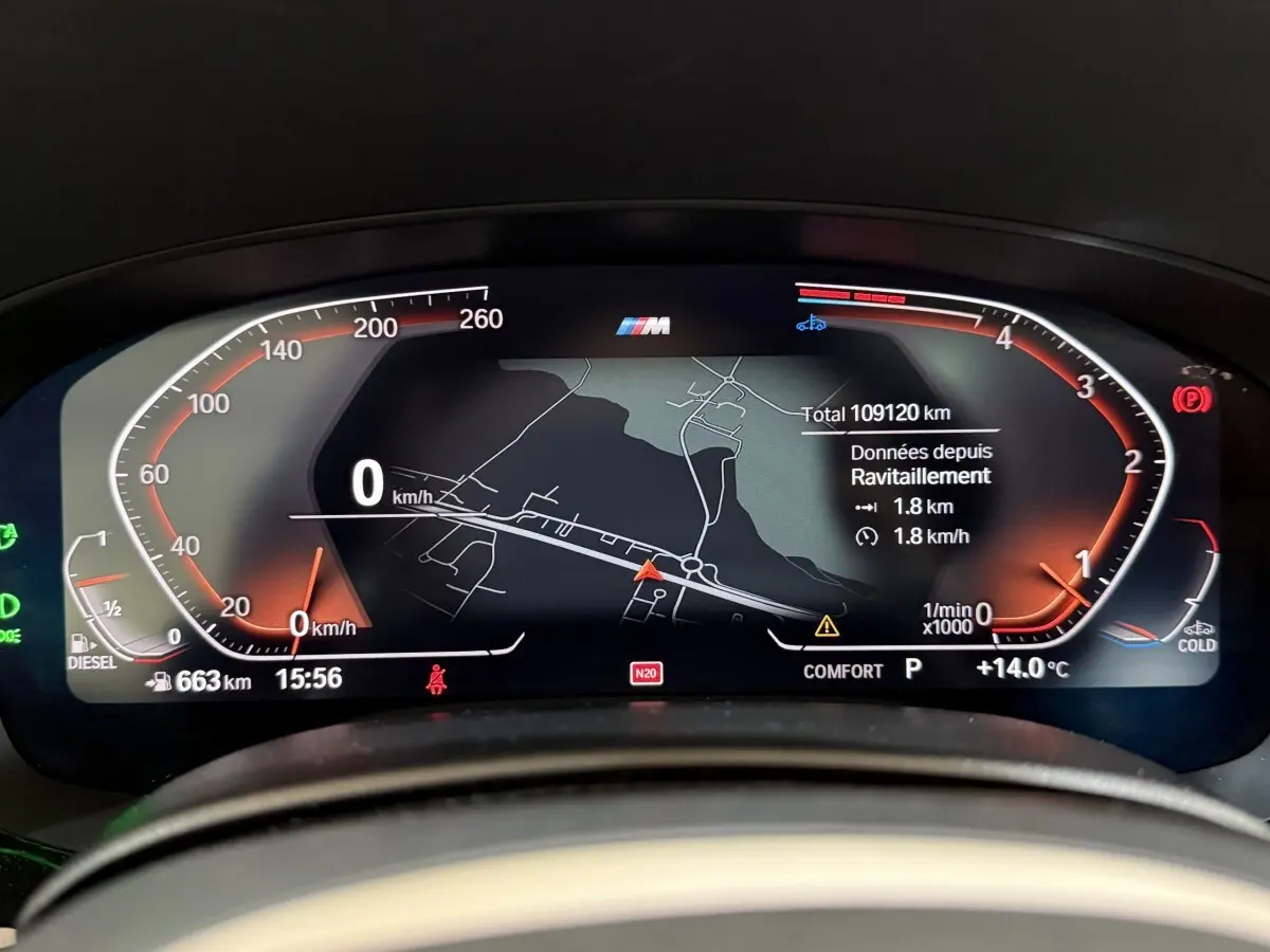 Affichage numérique du combiné d'instruments BMW Série 5 Touring 520d, avec navigation et compteurs rouges sur fond noir.