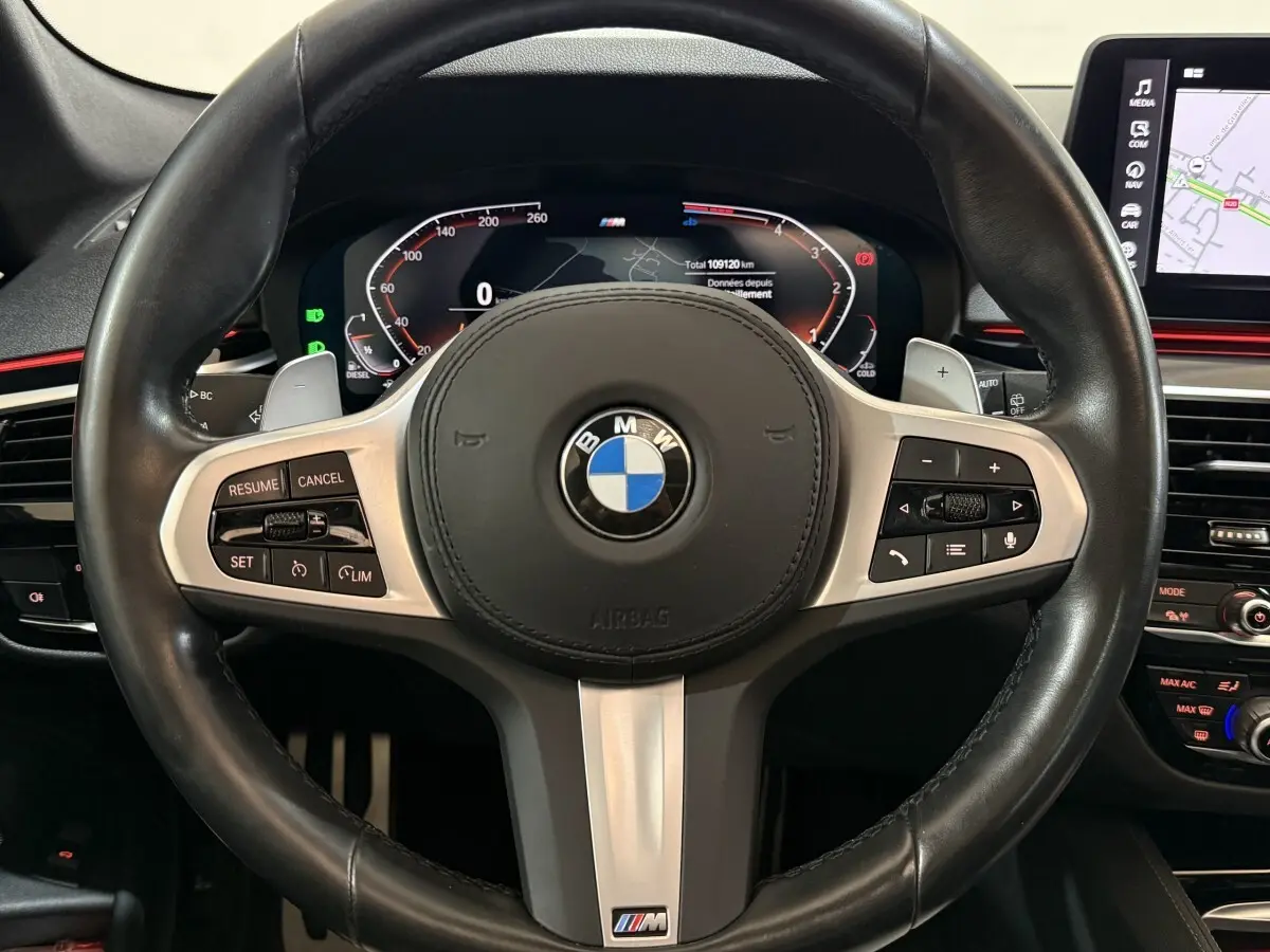 Vue rapprochée du volant cuir noir M Sport et du combiné d'instruments numérique de la BMW Série 5 Touring 520d 2023.