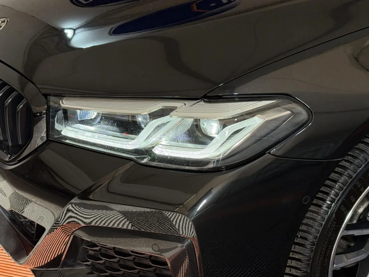 Gros plan sur le phare avant droit et la calandre noire brillante d'une BMW Série 5 Touring 520d M Sport 2023.