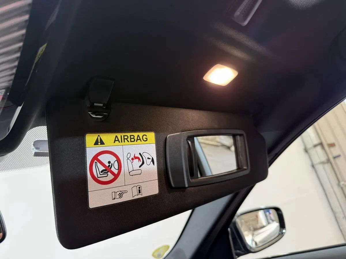 Détail du pare-soleil côté conducteur avec miroir intégré et avertissement airbag dans l’habitacle noir.