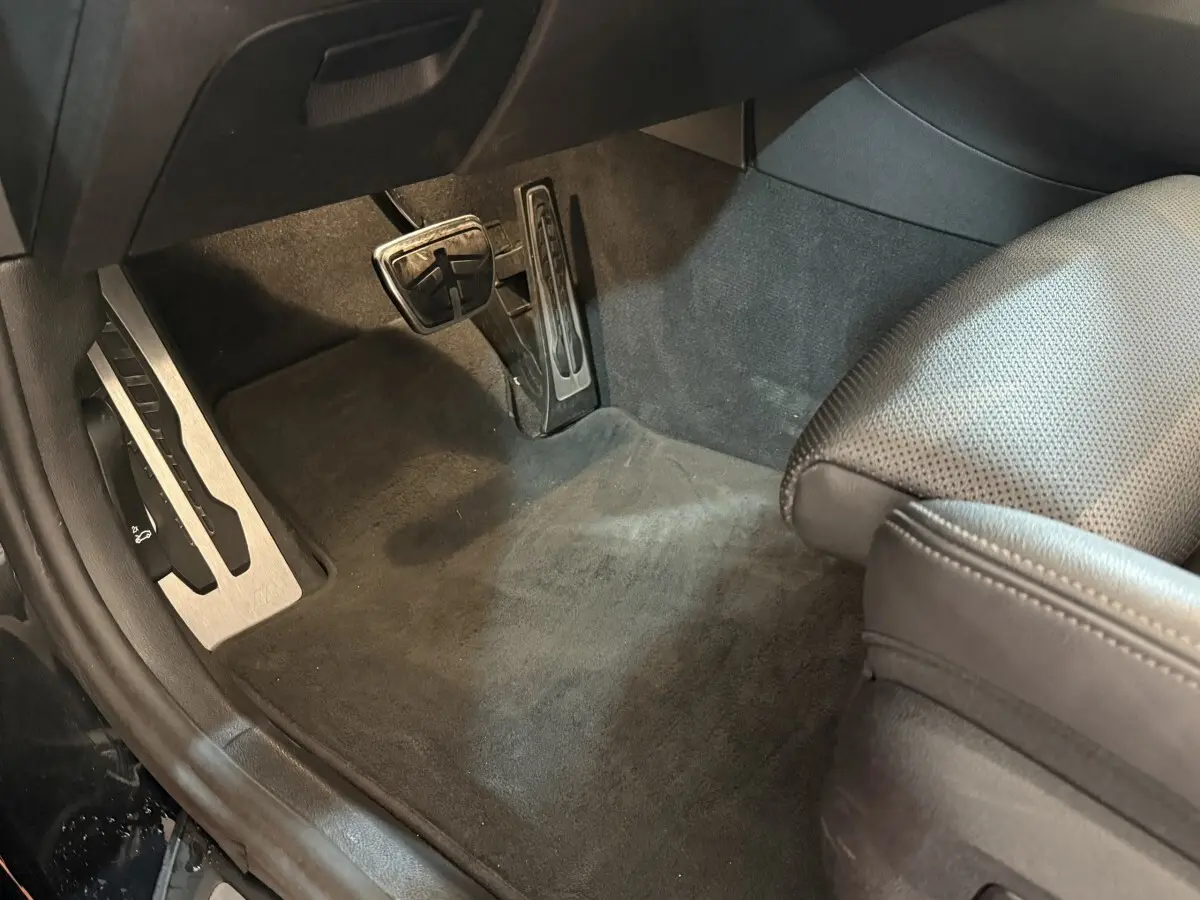 Vue rapprochée des pédales et du tapis noir côté conducteur de la BMW Série 5 Touring 520d M Sport 2023.