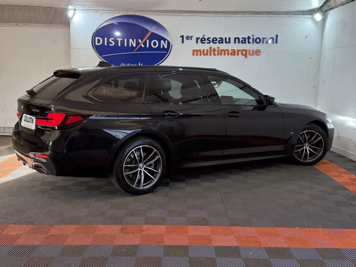 BMW Série 5 Touring 520d M Sport noire vue de profil côté gauche dans un showroom avec jantes sport et toit ouvrant.