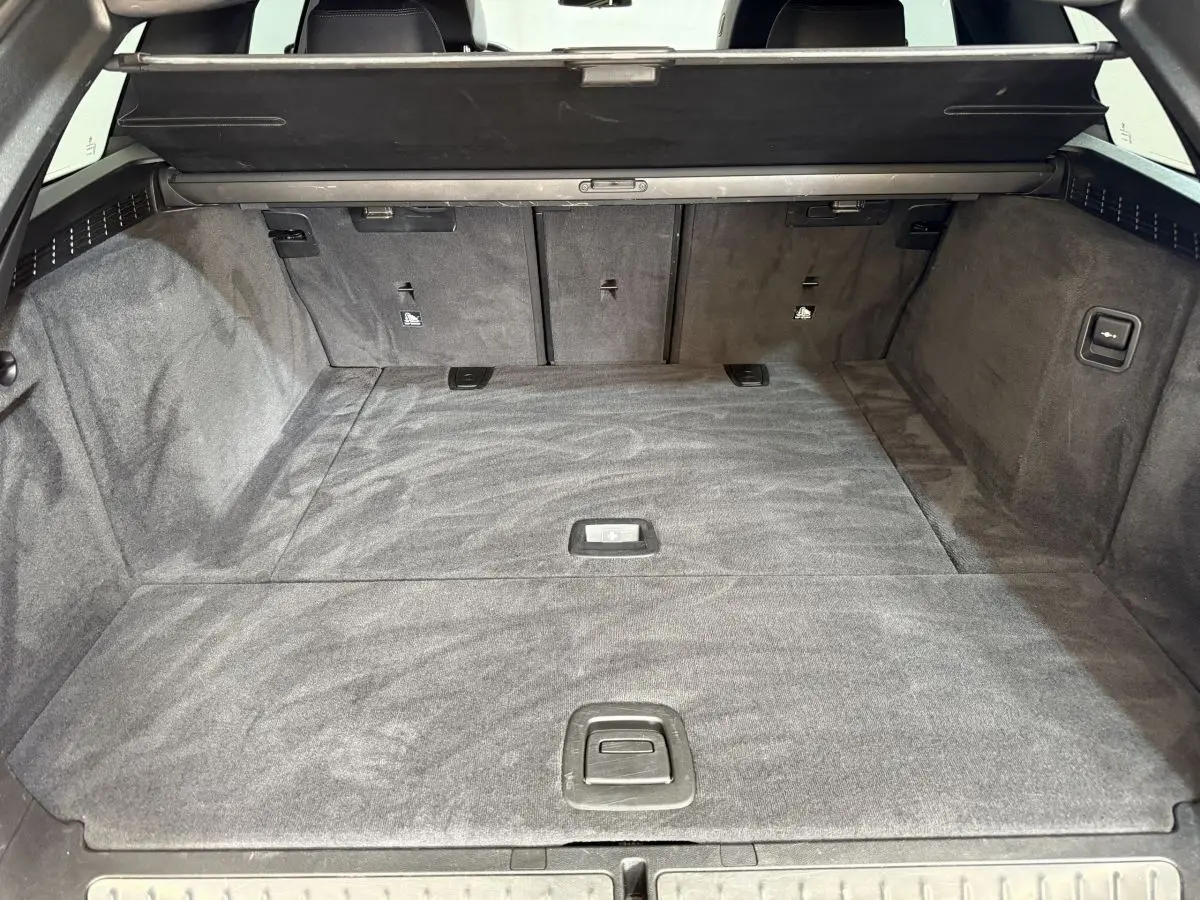 Vue intérieure du coffre spacieux et tapissé en noir de la BMW Série 5 Touring 520d M Sport 2023.