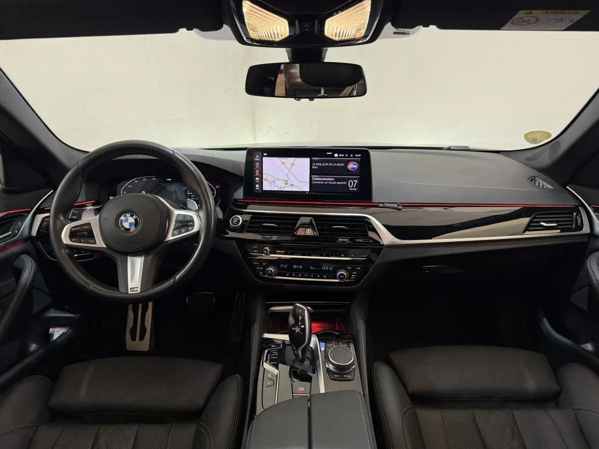 Vue frontale de l'intérieur noir de la BMW Série 5 Touring 520d M Sport 2023 avec écran tactile et volant multifonctions.