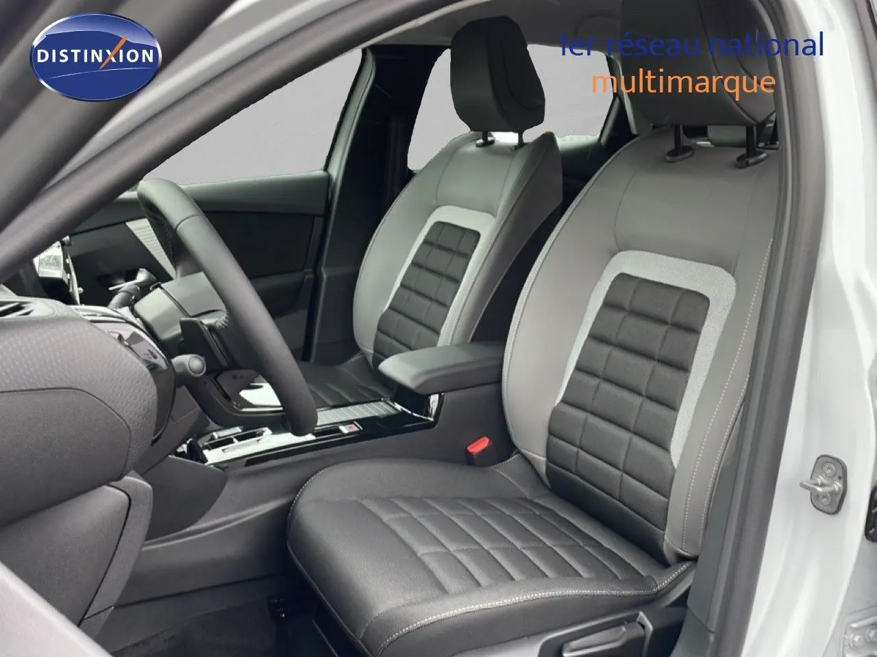 Vue intérieure côté conducteur de la Citroën C4 blanc métal, sièges en cuir noir et gris avec console centrale moderne.