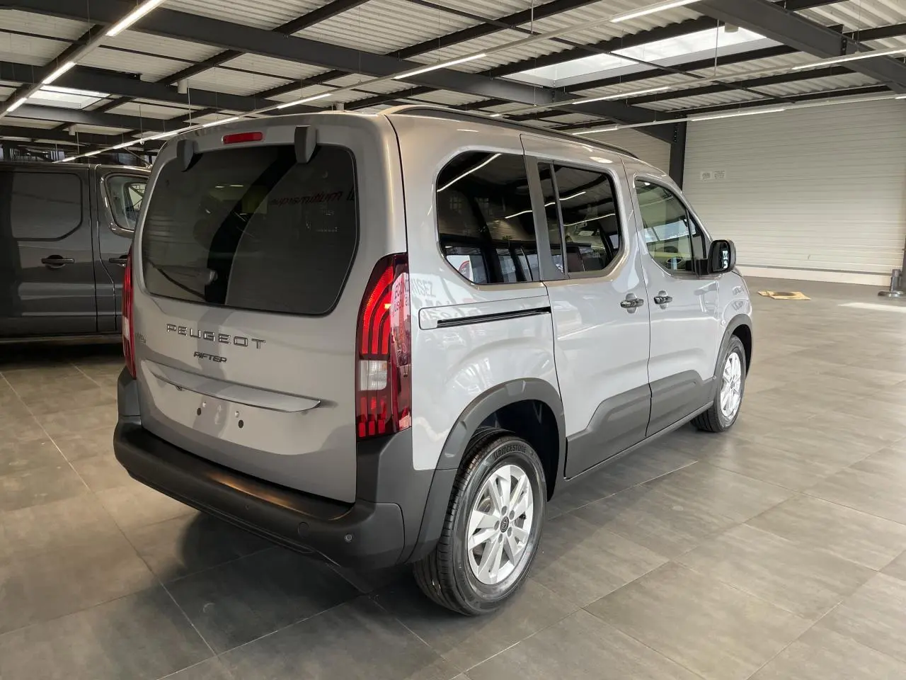 Peugeot Rifter gris Artense vu en 3/4 arrière droit, avec feux arrière LED et portes latérales coulissantes.