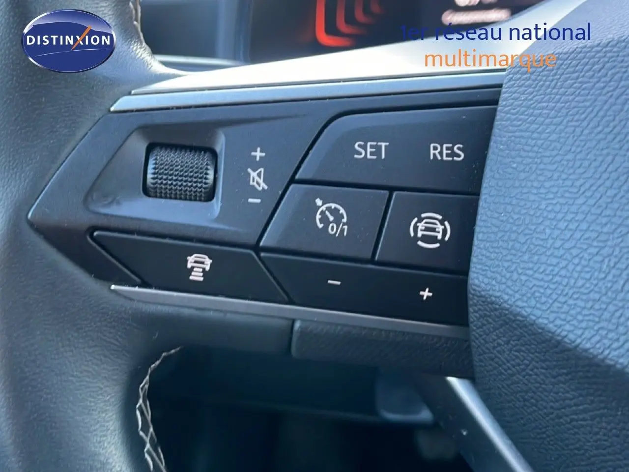 Gros plan sur les commandes au volant du SEAT Arona 2025 blanc toit gris, montrant les boutons de régulateur de vitesse et assistance conduite.